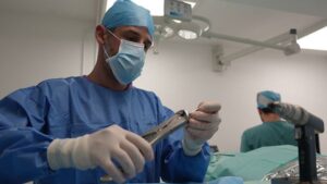 A veterinary surgeon is shown using equipment in a surgery room.