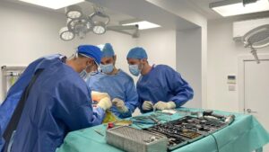Three veterinary surgeons work together over a surgical table with equipment around them.